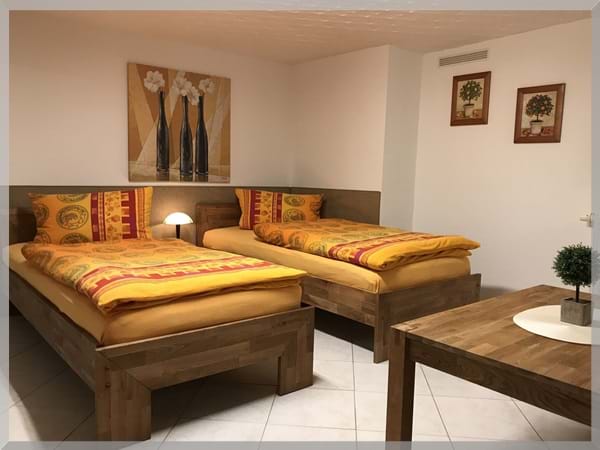 Großes Doppelbettzimmer der Pension Deparade Altenburg mit zwei Betten, Schreibtisch und gemütlicher Atmosphäre – ideal für Praktikanten und Langzeitgäste